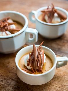 two white cups filled with food on top of a wooden table next to each other