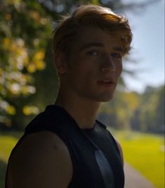 a young man standing in front of a tree looking at the camera with an intense look on his face