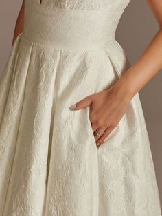 a woman in a white dress is holding her hand on the back of her dress