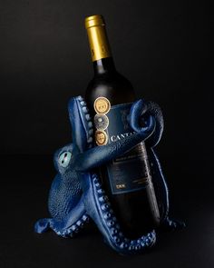 an octopus holding a bottle of wine in it's mouth and wrapped in blue fabric