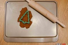 a cookie in the shape of a tree on top of a baking pan with a rolling pin