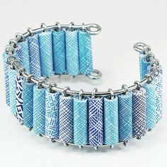 a blue and white bracelet with metal spikes on it's sides, in front of a white background