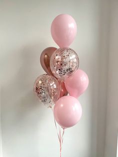 some pink and gold balloons are hanging from the ceiling in front of a white wall