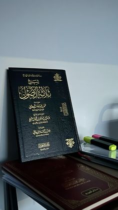 a book sitting on top of a desk next to a pen and marker holder in front of a white wall