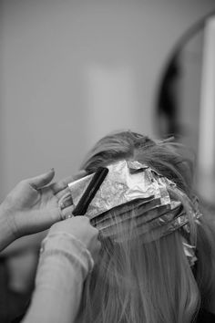 a woman is getting her hair cut by someone with a comb and paper wrapped around her head