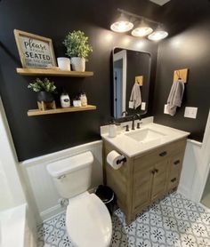 a white toilet sitting next to a sink in a bathroom under a mirror and lights