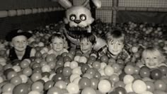 some children are in a ball pit with a stuffed animal and an adult rabbit behind them