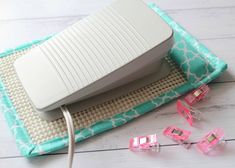 an electronic device sitting on top of a blue and white blanket next to pink glasses