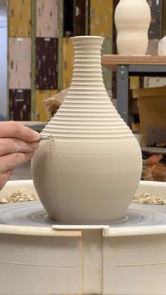 a person is making a vase out of clay