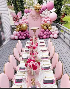 a table set up for a party with pink and gold decorations on the back wall