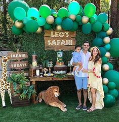 a man and woman standing in front of a dessert table with green balloons on it