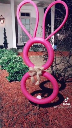 an inflatable pink bunny is sitting on top of the ground next to a house