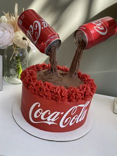 a coca - cola cake is decorated with flowers and two coke cans sticking out of it