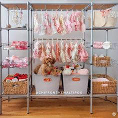 a teddy bear sitting on top of two baskets in front of a rack filled with baby clothes