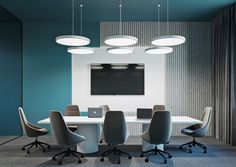 a conference room with blue walls and white table surrounded by chairs, laptops and a flat screen tv mounted on the wall