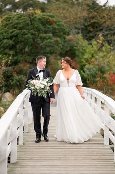 a bride and groom walking across a bridge