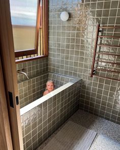 a small child is in the bathtub with his head sticking out from under the faucet