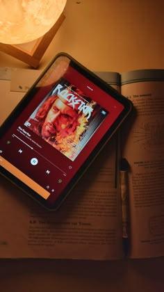 a tablet sitting on top of an open book next to a pen and light bulb