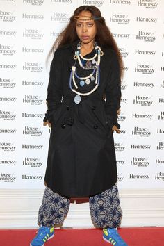 a woman standing in front of a red carpet wearing blue shoes and a black coat