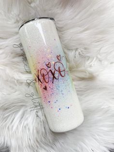 a pink and blue glitter tumbler sitting on top of a white fur covered floor