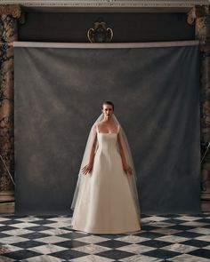 a woman in a wedding dress standing on a checkered floor