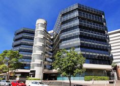 an office building with many windows and cars parked on the street in front of it