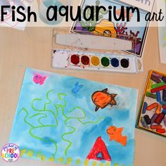 an art project for kids with fish and watercolors on the table next to it