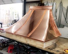 a copper hood sitting on top of a wooden table