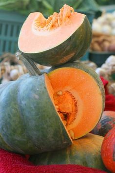 a pile of pumpkins sitting on top of each other in front of some vegetables