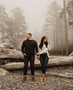 a man and woman standing next to each other holding hands in front of some trees