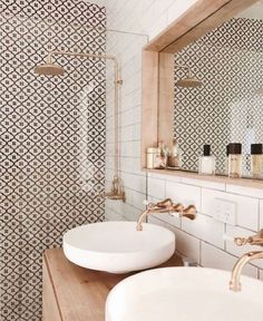 two white sinks sitting under a mirror in a bathroom next to a wooden counter top