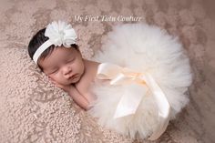 a newborn baby girl wearing a white tutu and headband