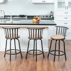 two stools in front of a kitchen island with white cabinets and black counter tops