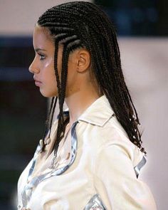 a woman with long dreadlocks standing in front of a wall and looking off to the side