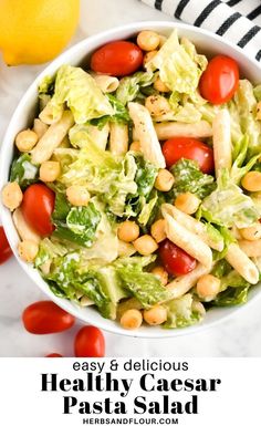 a white bowl filled with pasta salad next to a lemon and some cherry tomatoes on the side