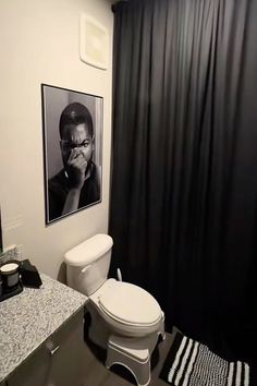 a white toilet sitting next to a black shower curtain