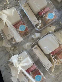 four clear boxes with various items in them on a marble counter top and tied together