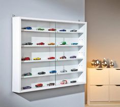 a white shelf filled with lots of toy cars