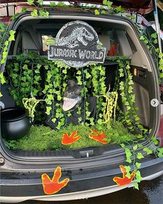 the trunk of a car with plants growing out of it's trunk and an image of a dinosaur