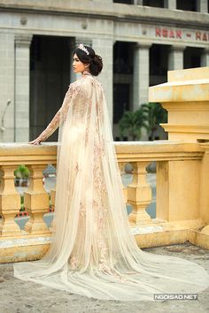 a woman in a wedding dress is standing on a balcony with her hand on the railing