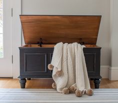 a blanket is laying on top of an old trunk with pom - poms