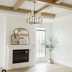 an empty living room with white walls and wood beams on the ceiling is shown in this image