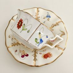 two tea cups and saucers sitting on top of each other in gold trimmings