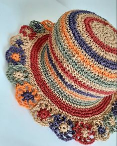 a multicolored crocheted hat laying on top of a white table