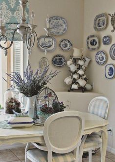 a dining room table with blue and white plates on the wall next to it,