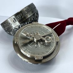 two silver watches sitting next to each other on top of a white surface with a red ribbon