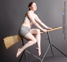 a woman is posing on a chair with a broom