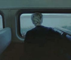 a person sitting on a train looking out the window at something in the distance,