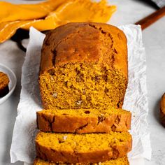 sliced loaf of pumpkin bread sitting on top of a white napkin next to two oranges