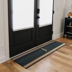 a black double door with two sidelights and a rug on the floor next to it